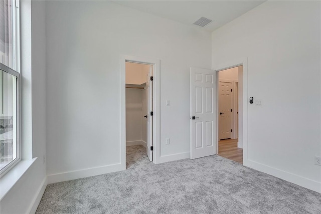 unfurnished bedroom featuring a walk in closet, baseboards, and carpet flooring