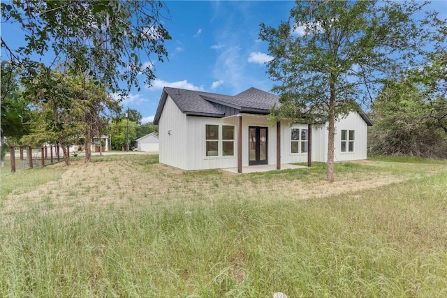 back of property featuring a shingled roof and a yard