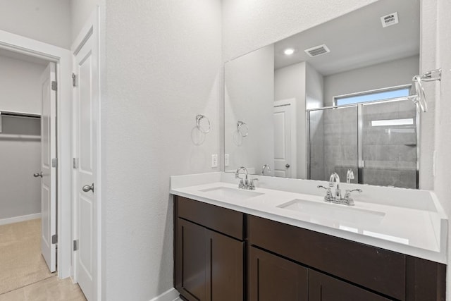 208 Lazy Lizzy Rd, Jarrell, TX 76537 - bathroom with double vanity, a shower stall, a walk in closet, and a textured wall