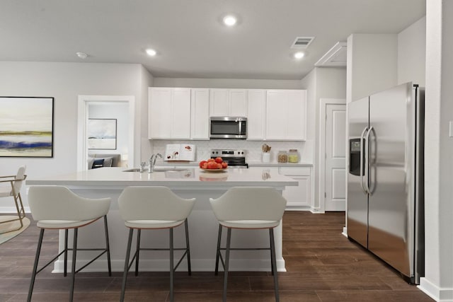 208 Lazy Lizzy Rd, Jarrell, TX 76537 - kitchen featuring appliances with stainless steel finishes, white cabinets, a kitchen breakfast bar, decorative backsplash, and recessed lighting