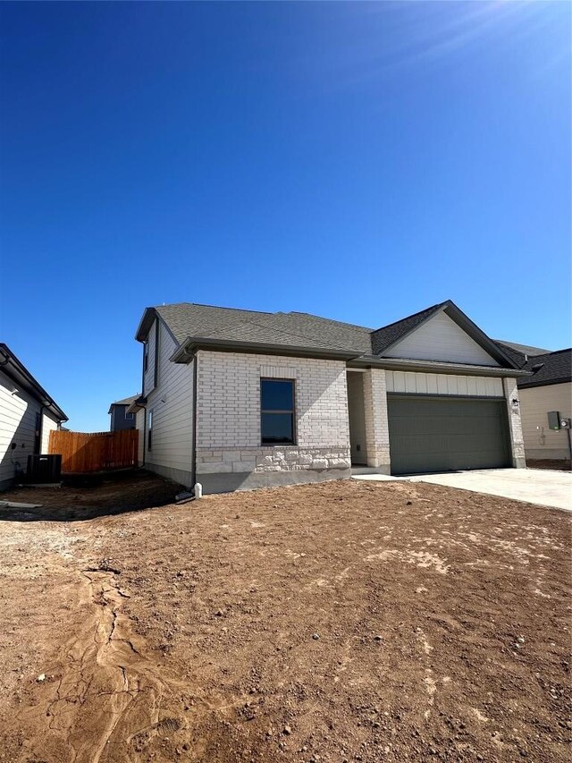 ranch-style home featuring driveway, fence, brick siding, a garage, and a shingled roof