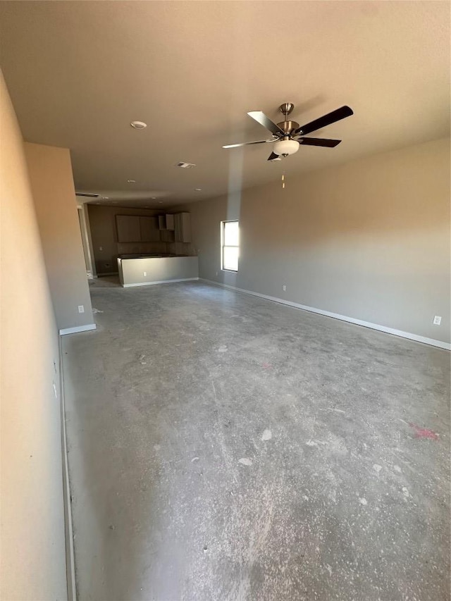 unfurnished living room featuring concrete flooring, baseboards, and ceiling fan