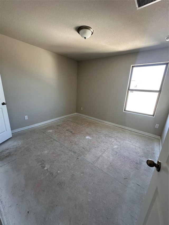 spare room with baseboards, a textured ceiling, and visible vents