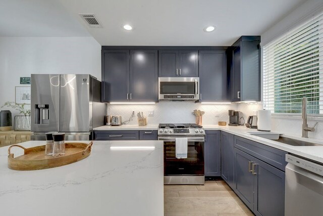 413 W Odell St Unit 2, Austin, TX 78752 - kitchen featuring stainless steel appliances, a sink, decorative backsplash, light stone counters, and recessed lighting