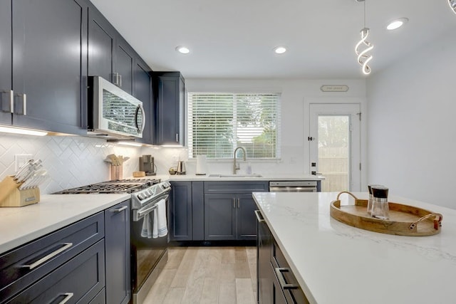 kitchen with recessed lighting, stainless steel appliances, a sink, light wood-style floors, and decorative backsplash