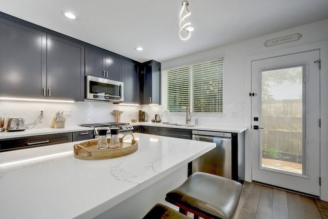 kitchen featuring a wealth of natural light, a sink, backsplash, and appliances with stainless steel finishes