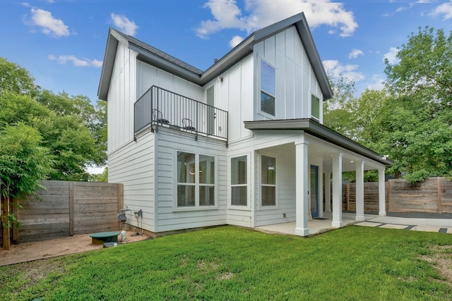 back of property with board and batten siding, a fenced backyard, a patio, and a balcony