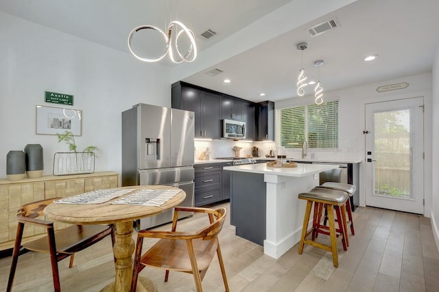 413 W Odell St Unit 2, Austin, TX 78752 - kitchen featuring stainless steel appliances, a chandelier, tasteful backsplash, light countertops, and a kitchen bar