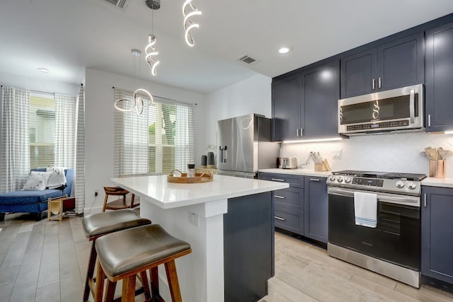 kitchen with light wood-style flooring, a breakfast bar, stainless steel appliances, light countertops, and visible vents