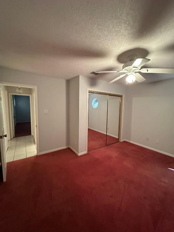 unfurnished bedroom featuring ceiling fan, baseboards, a closet, and carpet flooring