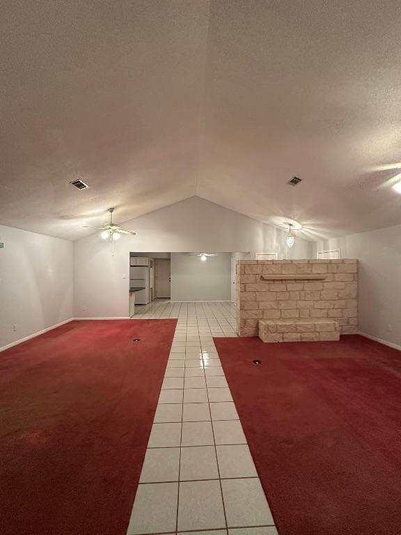 interior space with vaulted ceiling, a ceiling fan, light tile patterned flooring, baseboards, and visible vents