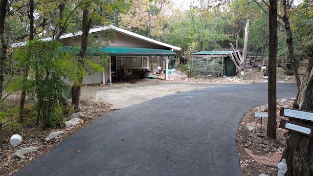 exterior space with a forest view and aphalt driveway