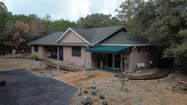 rear view of property with a patio area, roof with shingles, and stucco siding