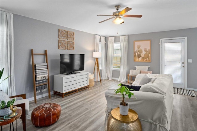 living area featuring wood finished floors, a ceiling fan, and baseboards