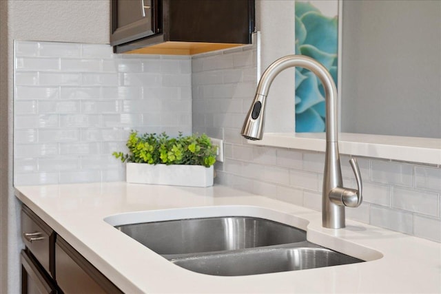 details featuring light countertops, dark brown cabinets, decorative backsplash, and a sink