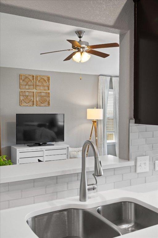 kitchen with ceiling fan, a sink, and light countertops