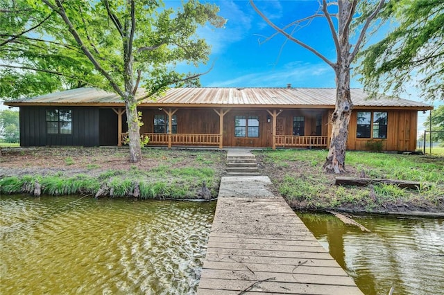 rear view of property featuring metal roof, a water view, board and batten siding, and covered porch