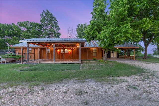 back of house with a carport, a lawn, driveway, and metal roof