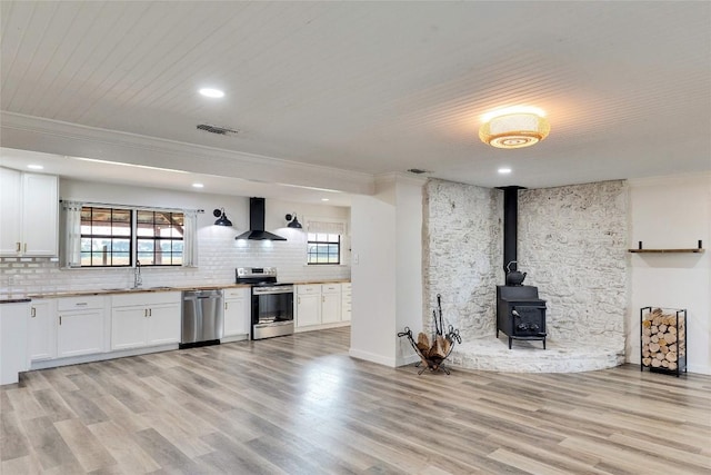 unfurnished living room with ornamental molding, light wood finished floors, a sink, and visible vents