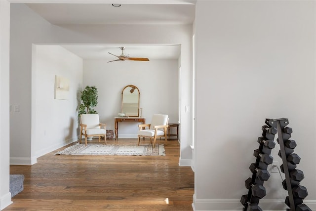 living area with baseboards, a ceiling fan, and wood finished floors