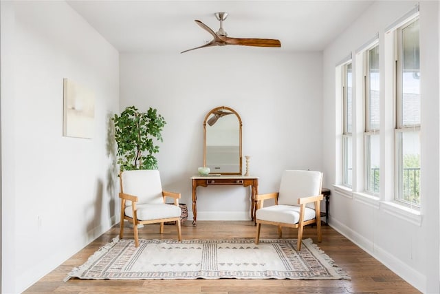 sitting room with baseboards, a ceiling fan, and wood finished floors