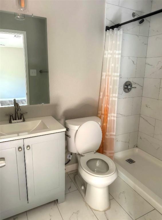 full bath with a shower stall, marble finish floor, vanity, and toilet