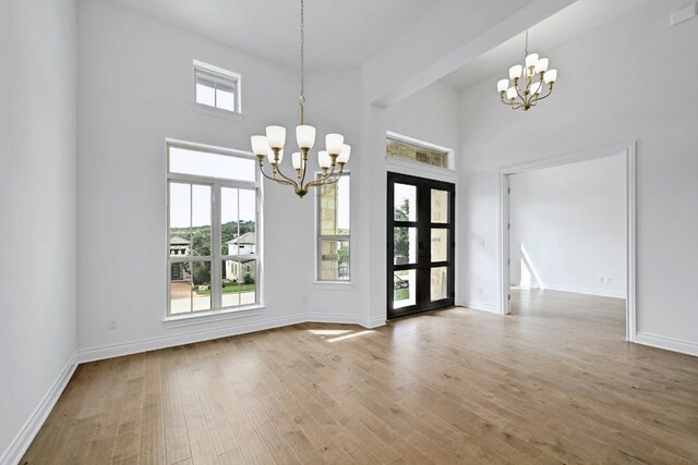 905 Crestone Stream Dr, Austin, TX 78738 - unfurnished dining area with a chandelier, a towering ceiling, and wood finished floors