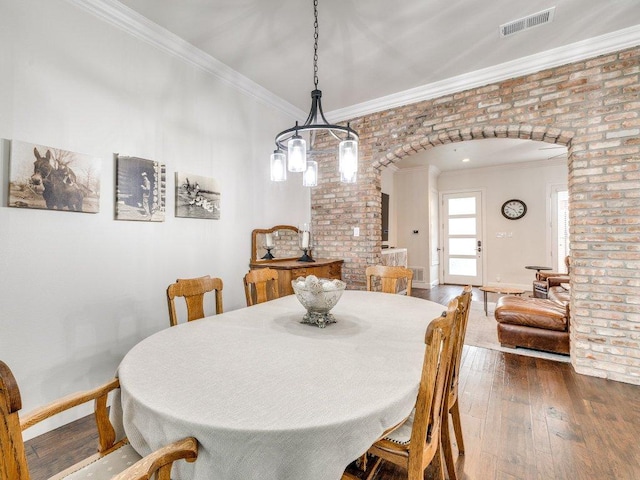 dining room with arched walkways, baseboards, visible vents, crown molding, and hardwood / wood-style flooring