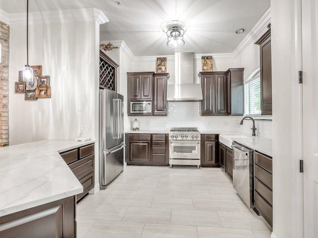 kitchen with wall chimney range hood, dark brown cabinets, premium appliances, a sink, and decorative backsplash