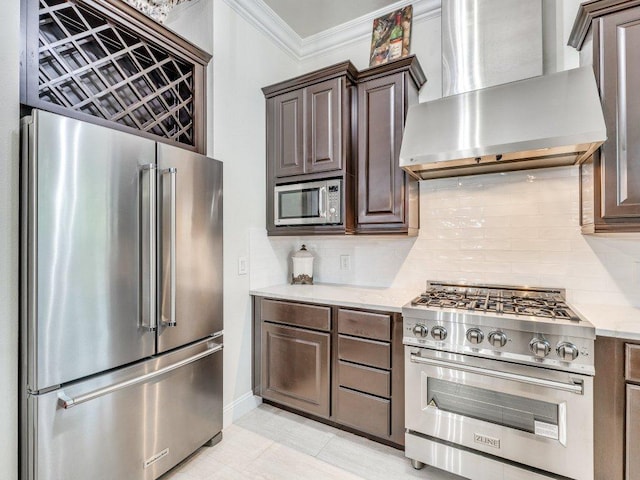 1202 S Flores St Unit 102, San Antonio, TX 78204 - kitchen featuring premium appliances, wall chimney exhaust hood, crown molding, tasteful backsplash, and dark brown cabinets