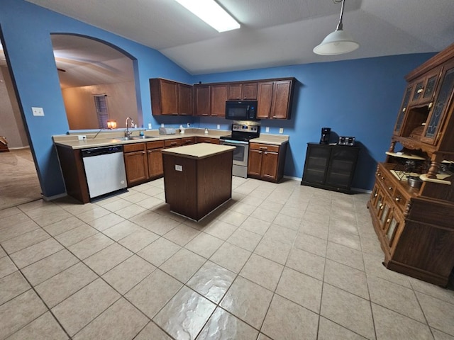114 Mossy Rock Cv, Hutto, TX 78634 - kitchen featuring appliances with stainless steel finishes, lofted ceiling, arched walkways, light countertops, and a kitchen island