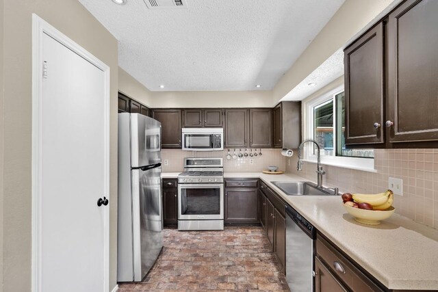 2814 Buckeye Trl, Cedar Park, TX 78613 - kitchen featuring stainless steel appliances, a sink, dark brown cabinets, backsplash, and a textured ceiling