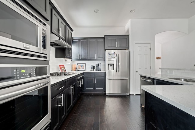 3905 Veneto Cir, Leander, TX 78641 - kitchen with appliances with stainless steel finishes, light stone countertops, backsplash, dark wood-style floors, and recessed lighting