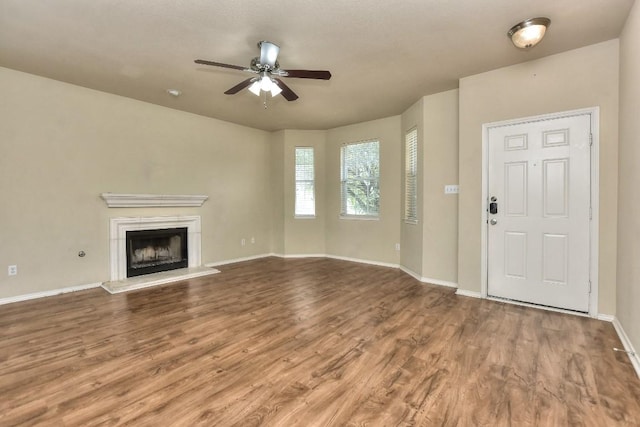 2625 Summerwalk Pl, Round Rock, TX 78665 - unfurnished living room with ceiling fan, wood finished floors, a fireplace with raised hearth, and baseboards