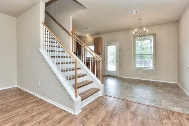entryway featuring wood finished floors, visible vents, an inviting chandelier, and stairway