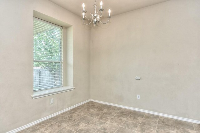 empty room featuring baseboards and a notable chandelier