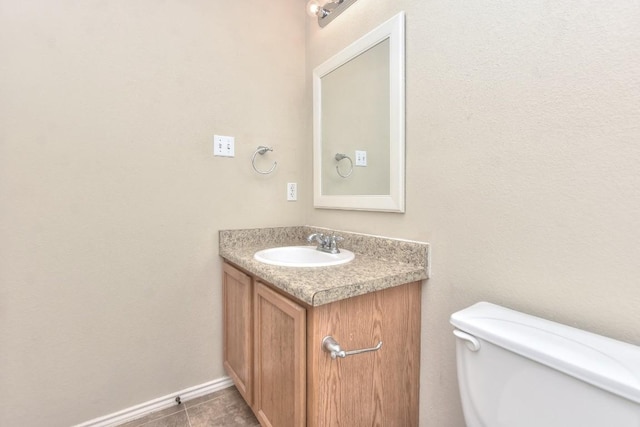 half bath with baseboards, vanity, tile patterned flooring, and toilet