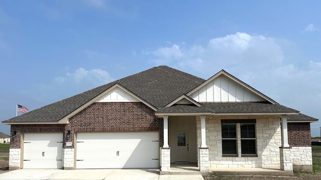 view of front facade with stone siding, driveway, roof with shingles, and a garage
