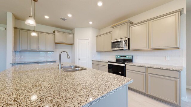 kitchen with light stone counters, visible vents, stainless steel appliances, and a sink