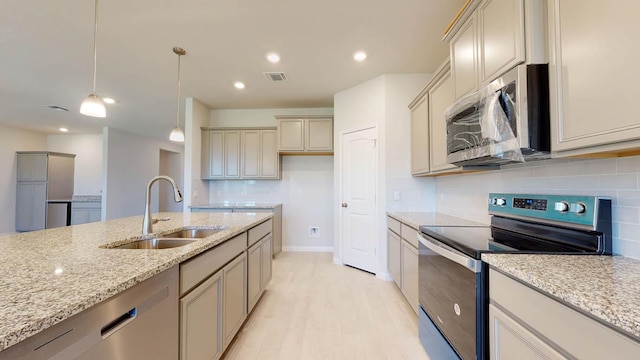 kitchen with backsplash, light stone countertops, stainless steel appliances, and a sink