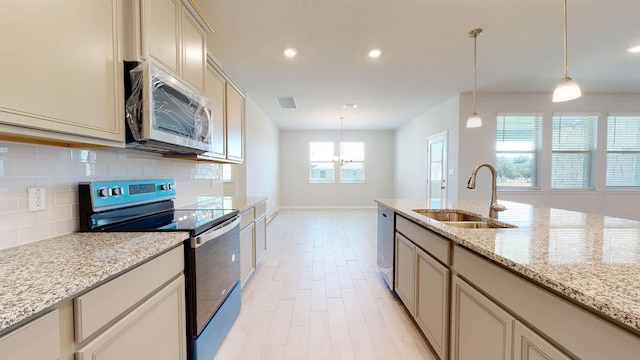 kitchen featuring stainless steel appliances, a sink, tasteful backsplash, baseboards, and a notable chandelier