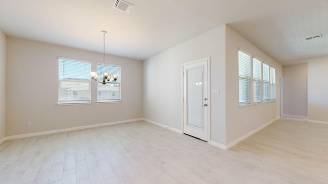 spare room with light wood-type flooring, visible vents, baseboards, and an inviting chandelier