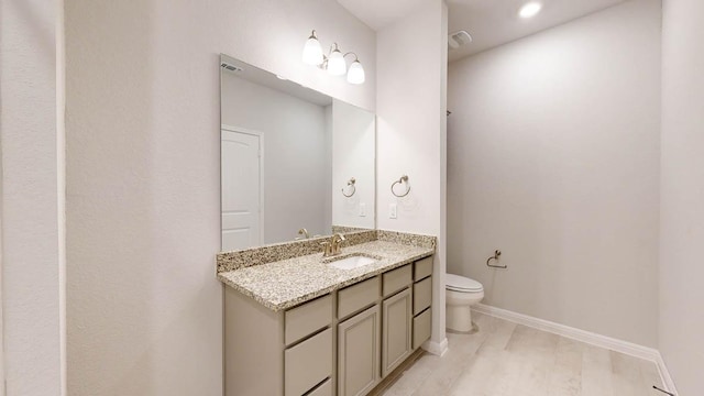 bathroom with baseboards, toilet, vanity, and wood finished floors