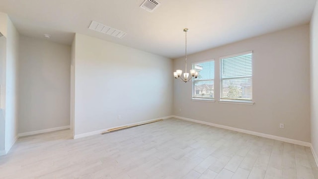spare room featuring light wood-type flooring, visible vents, and a notable chandelier