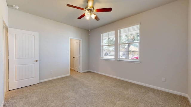 carpeted spare room featuring a ceiling fan and baseboards