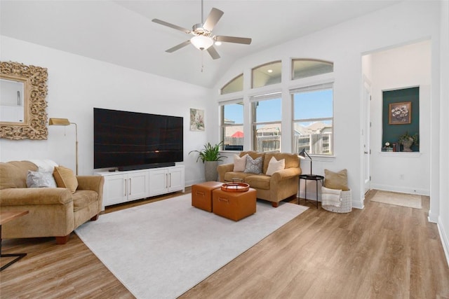 living room featuring light wood-style flooring, baseboards, high vaulted ceiling, and a ceiling fan