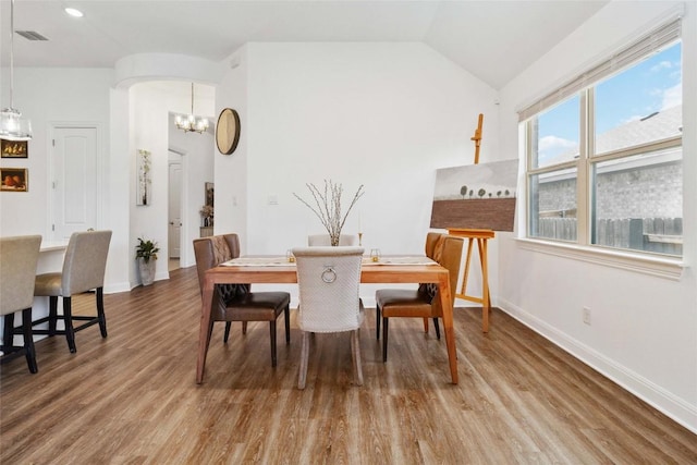 dining room with wood finished floors, arched walkways, an inviting chandelier, baseboards, and visible vents