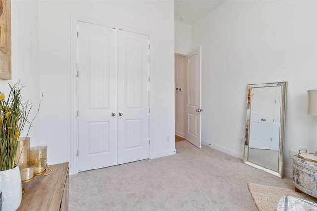 unfurnished bedroom with baseboards, light carpet, and a closet