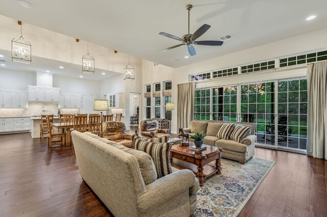 living area featuring visible vents, a ceiling fan, dark wood-style floors, and a high ceiling