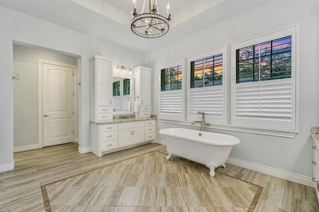 full bathroom with a soaking tub, baseboards, vanity, and an inviting chandelier